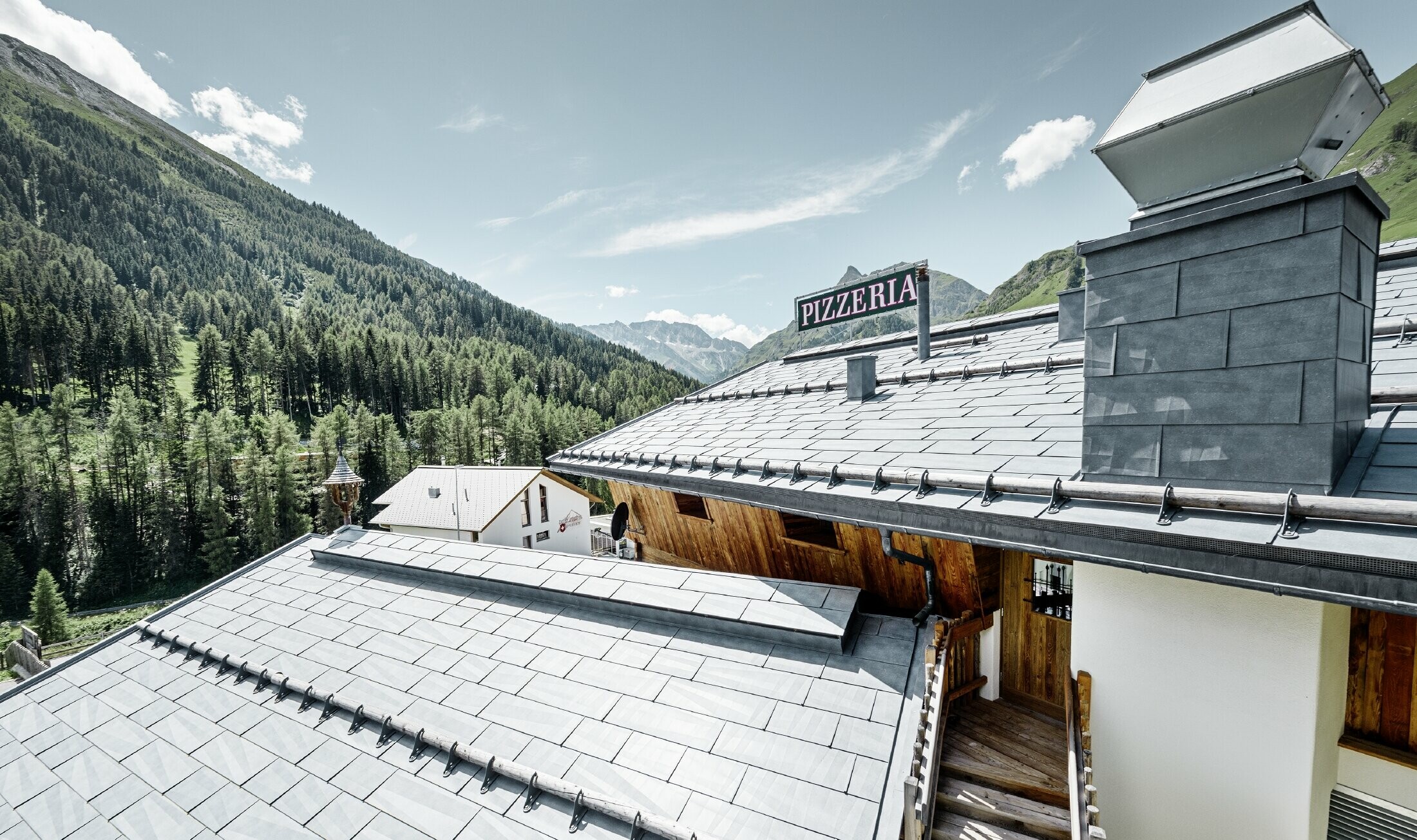 Restaurang Almrausch med utsikt över bergen och ett PREFA-tak med takpanelen FX.12 i stengrått och snörasskydd