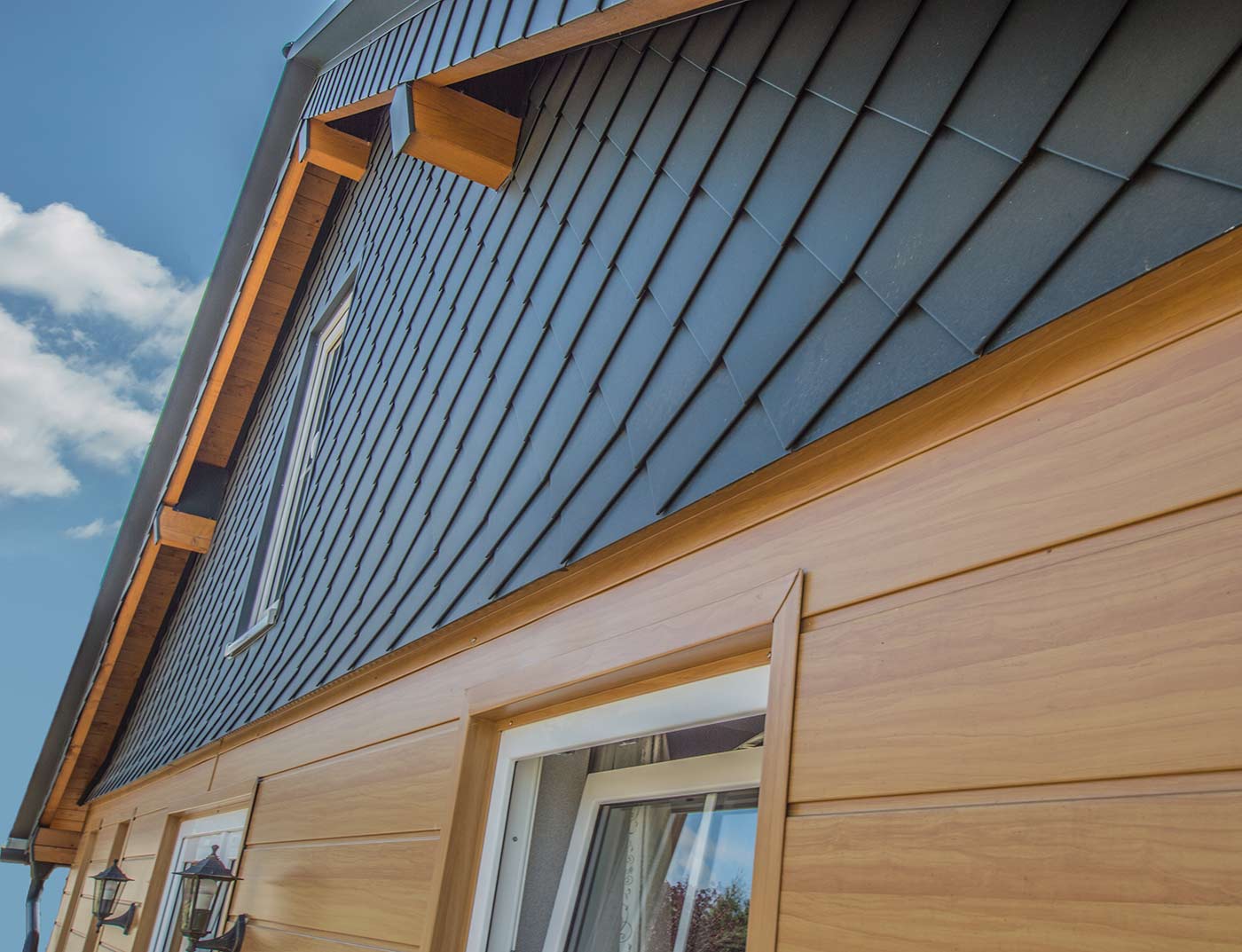 PREFA väggdesign med sidings i ljust trä, samt en inklädd gavel i antracit med PREFA-väggromber 20 × 20.